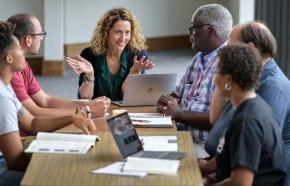 Professor talks with students around table in classroom